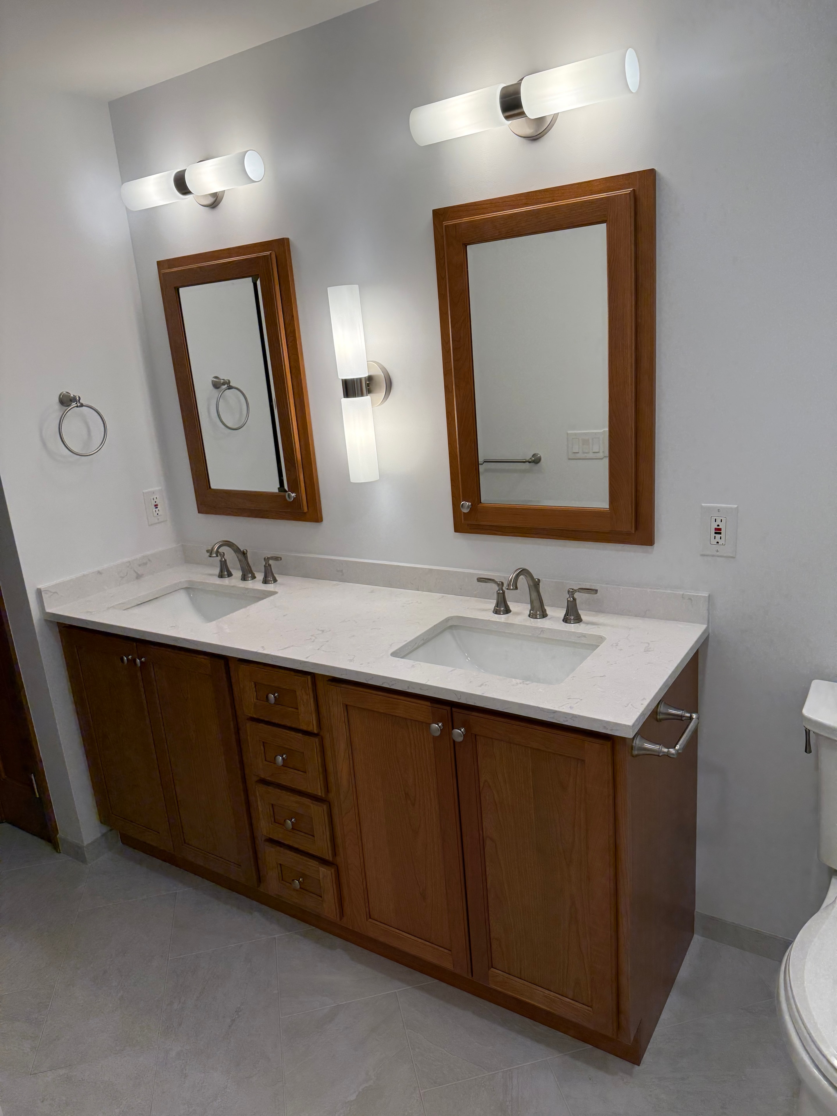 Clifton Park bathroom remodel - wide vanity view with wood cabinetry tower, dual mirrors, and marble quartz countertop