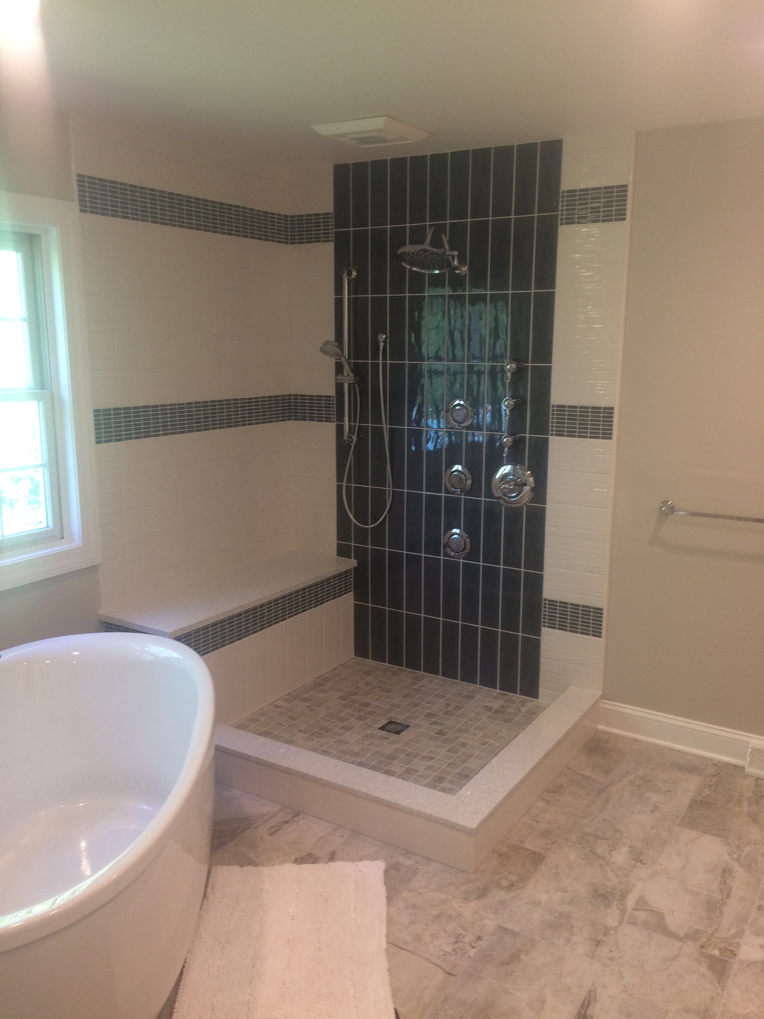 Niskayuna bathroom remodel - spa shower wall with dark subway tile, body jets, and mosaic tile accents