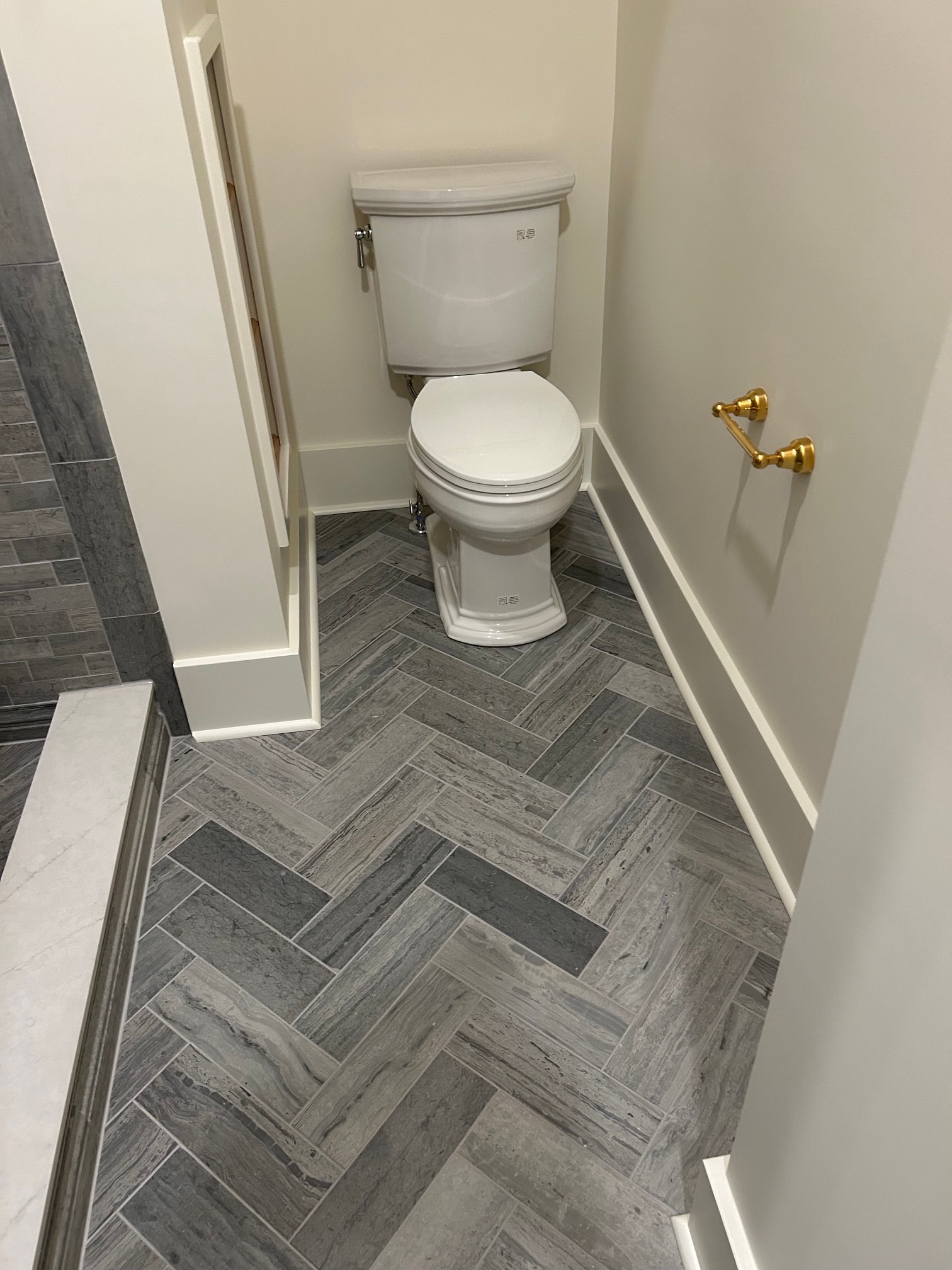 Niskayuna sauna and spa bathroom - toilet area with gray herringbone floor tile and brass ceiling fixture