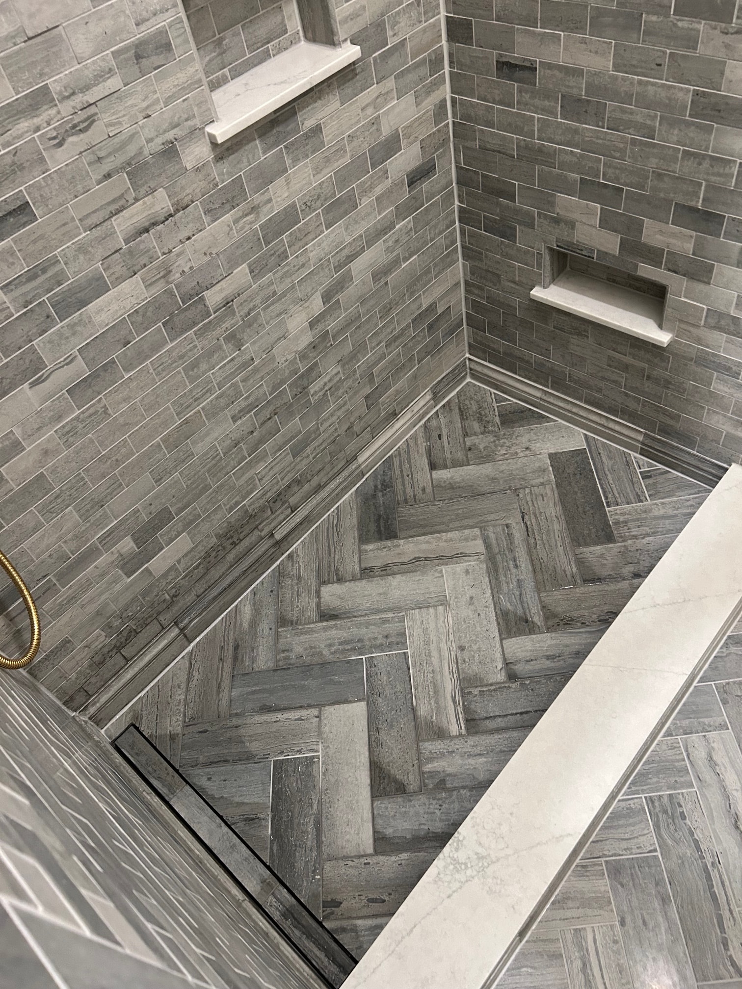 Niskayuna sauna and spa bathroom - overhead view of shower floor with linear drain transitioning to herringbone tile