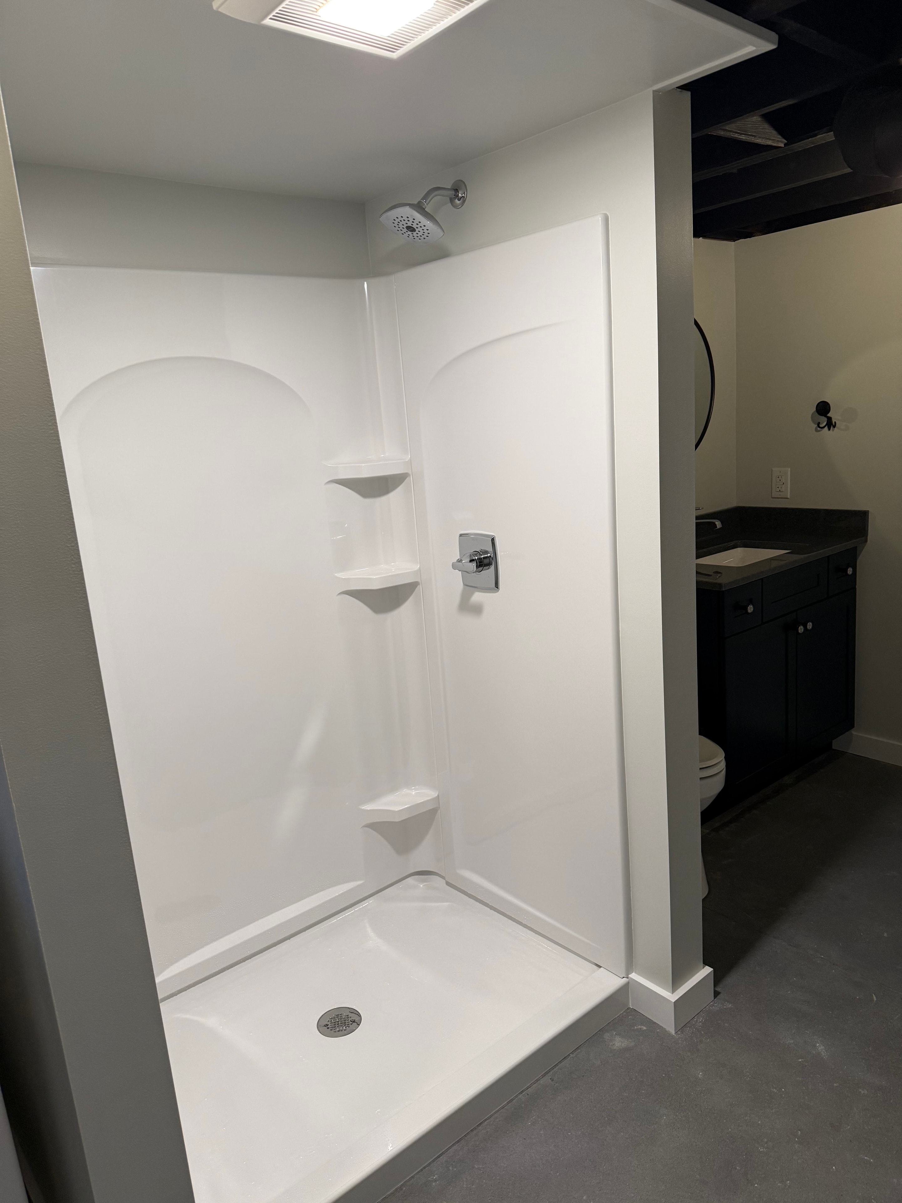 Schuylerville basement bathroom - overhead view of white tub and shower unit with chrome fixtures and built-in seat