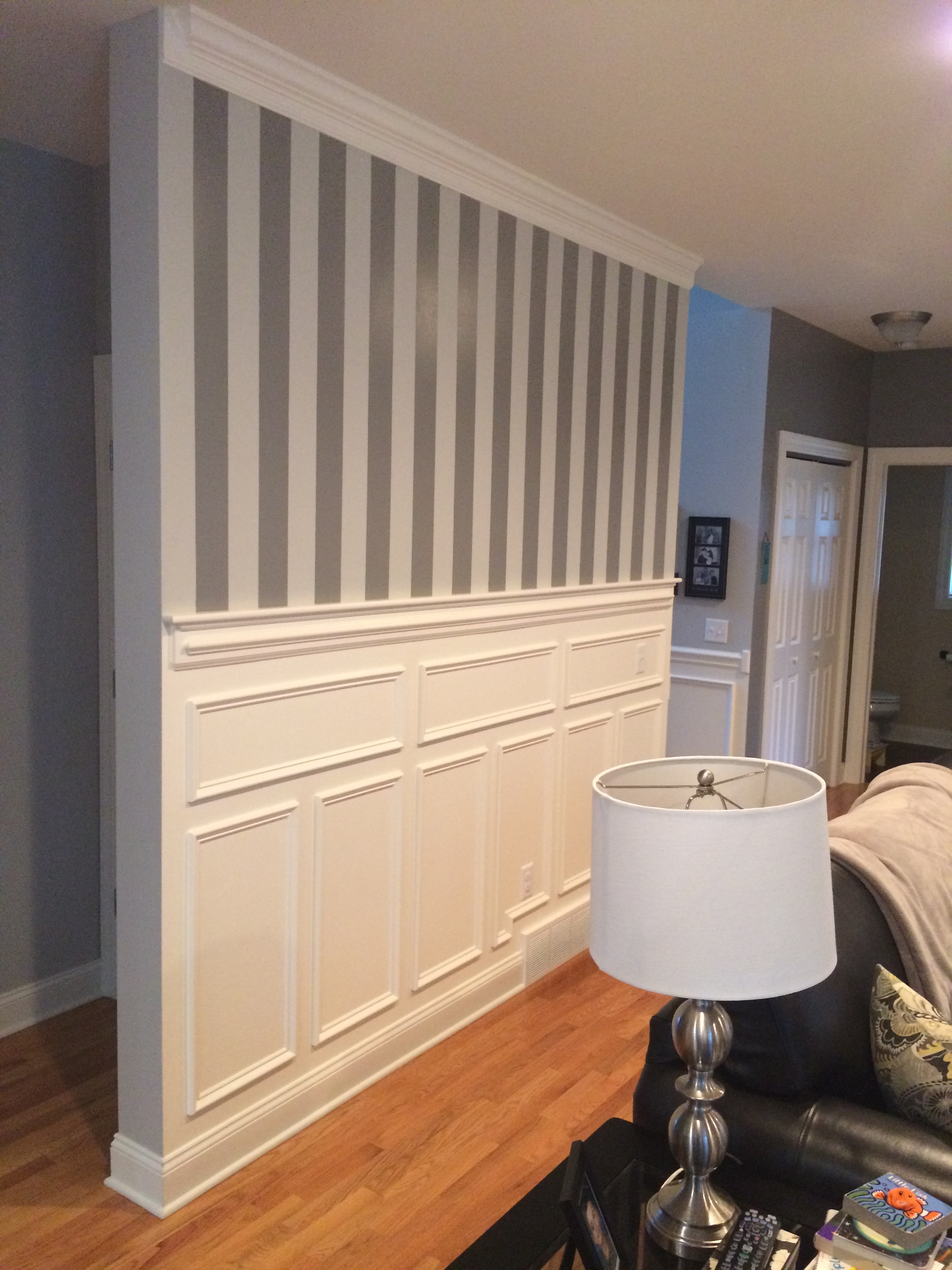 Altamont accent wall bedroom - horizontal painted stripes on left half, raised panel wainscoting on right half, crown molding, hardwood floor