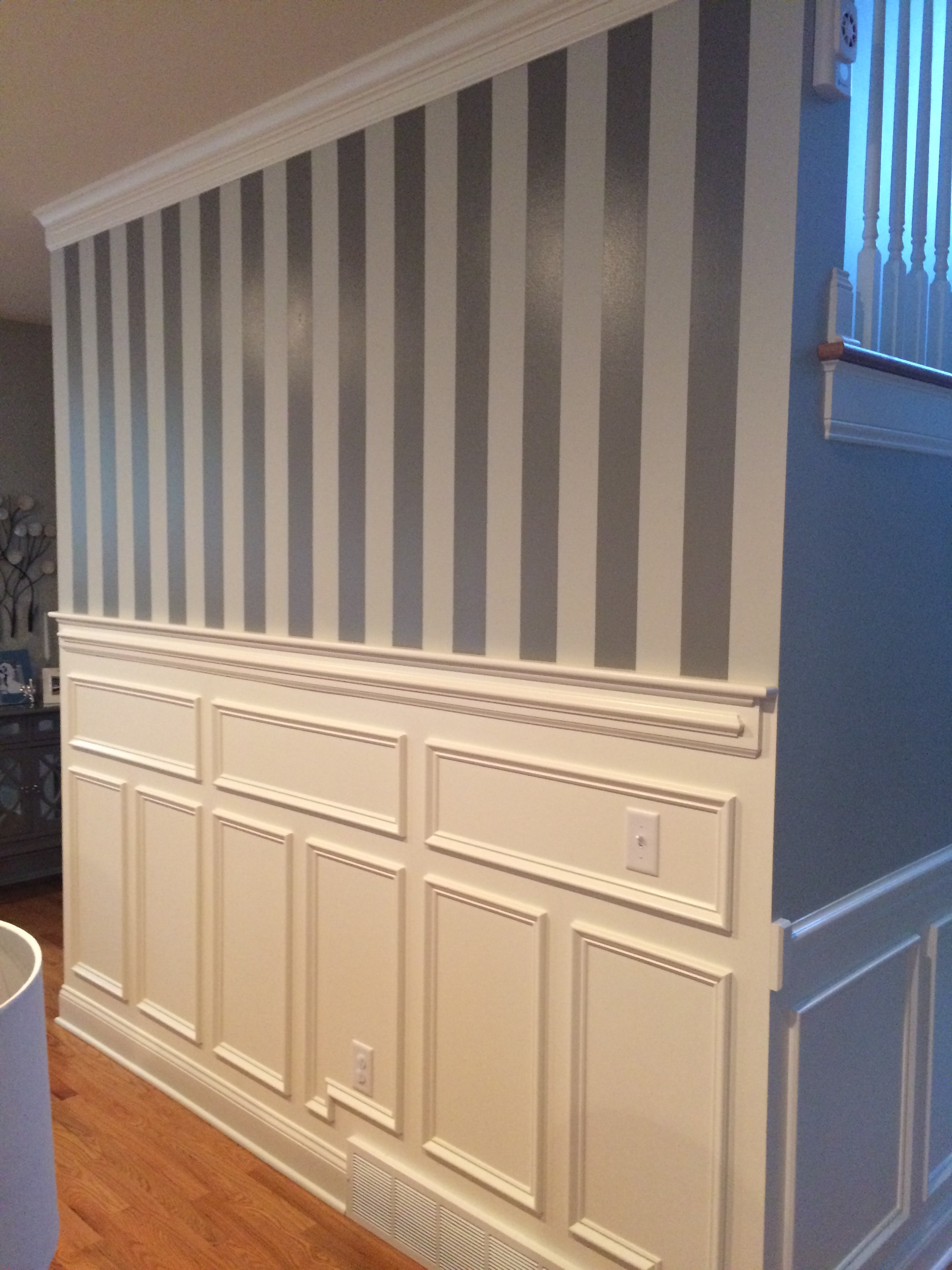 Altamont accent wall full view - painted horizontal stripes meeting raised panel wainscoting with crown molding and hardwood floor