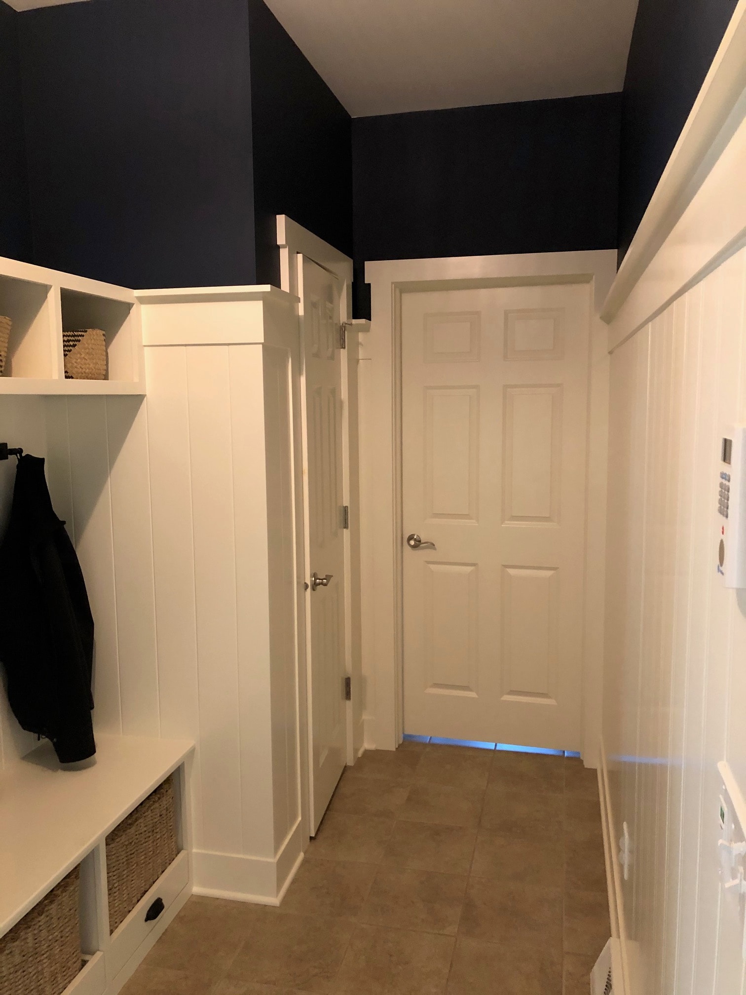 Altamont mudroom wide view showing shiplap walls, raised panel cabinet doors, built-in bench with woven basket cubbies, and navy accent wall