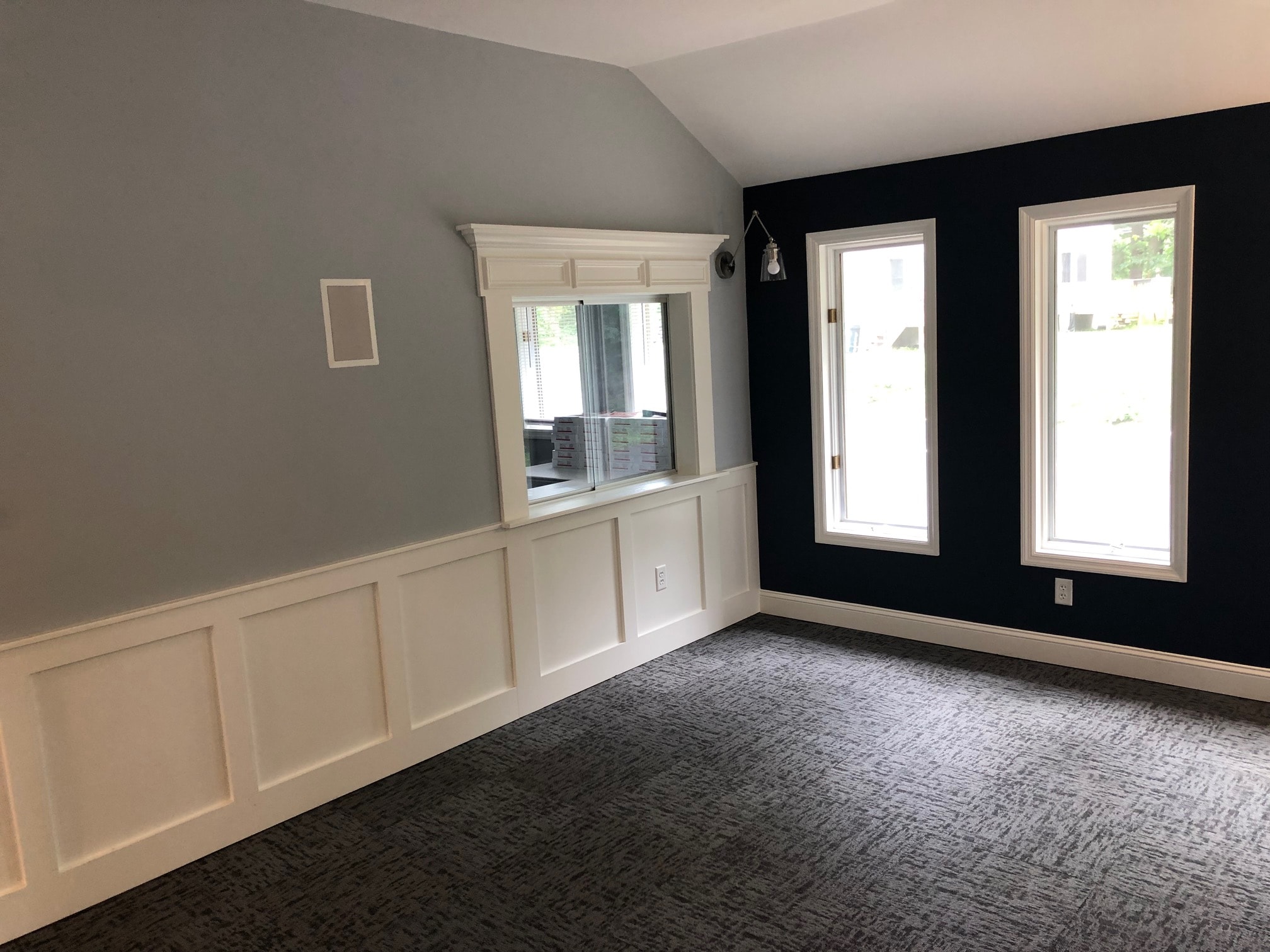 Colonie office remodel with white board and batten wainscoting, custom service window surround with crown molding, navy accent wall, and vaulted ceiling