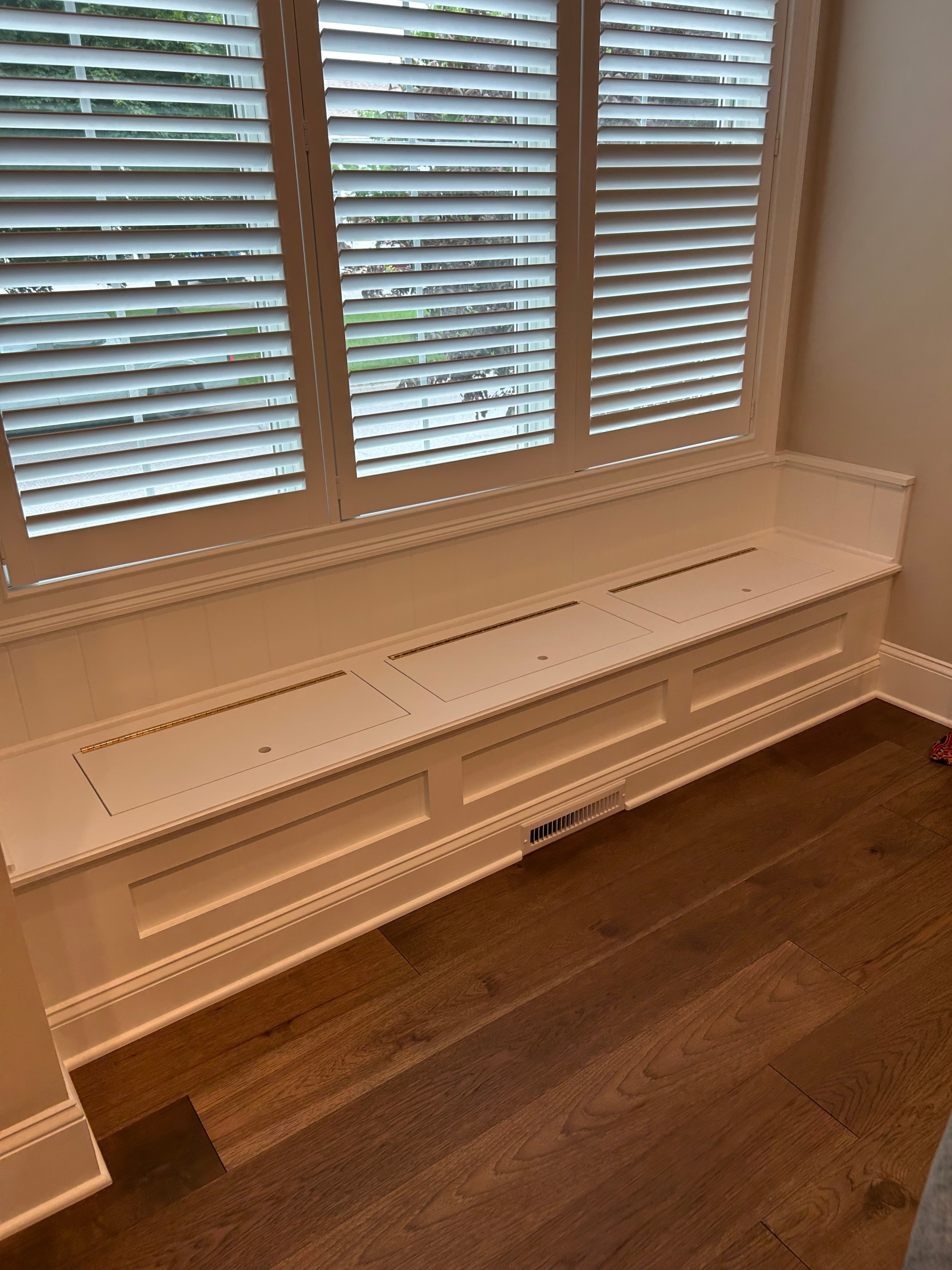 Saratoga Springs window seat raised panel storage bench with crown molding surround and warm oak hardwood floor