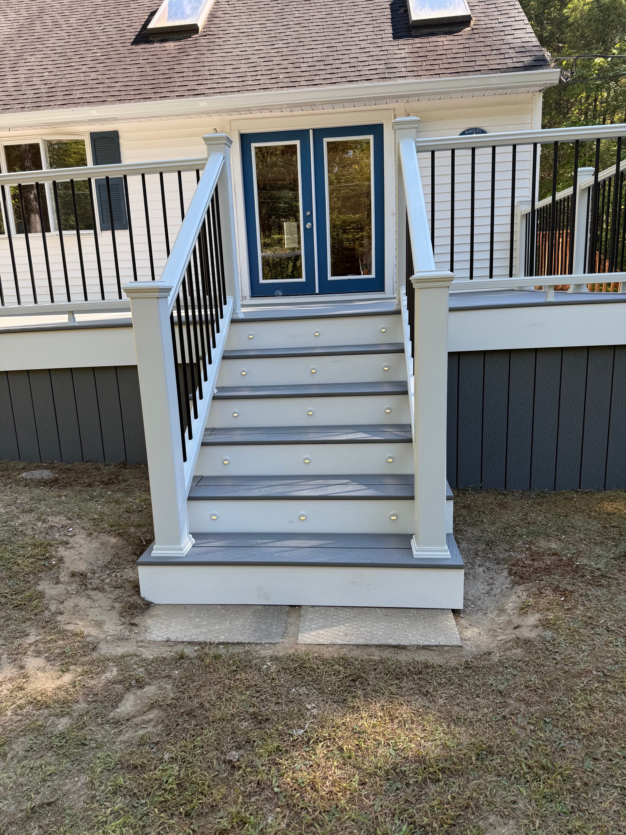 Schroon Lake deck railing post detail with LED cap lighting, black aluminum balusters, white PVC posts, and navy blue door surround