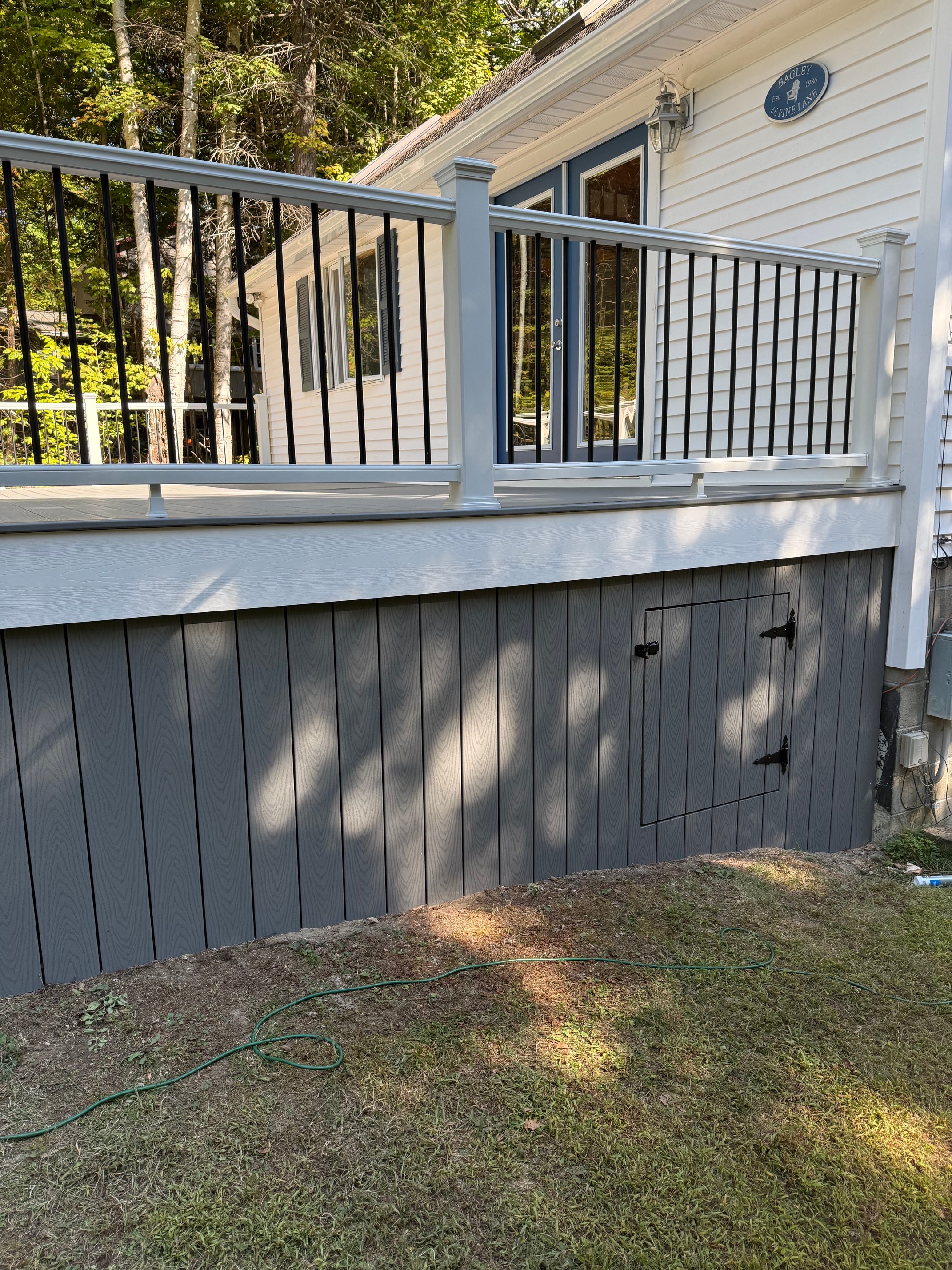 Schroon Lake deck gray composite decking surface with access hatch, white PVC railing, and black aluminum balusters