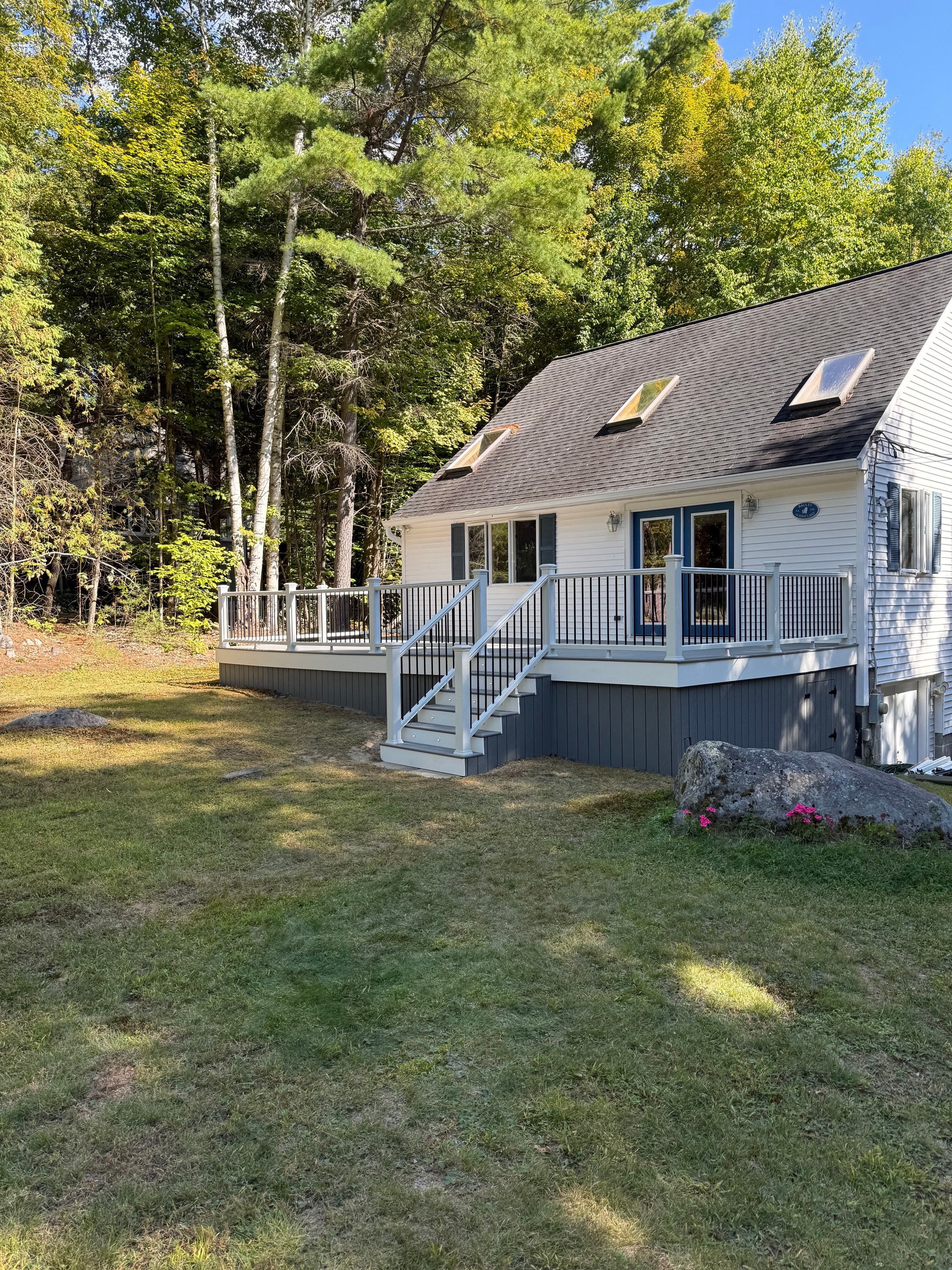 Schroon Lake deck full exterior view showing composite deck, white railing, integrated stairs, and wooded lake house setting