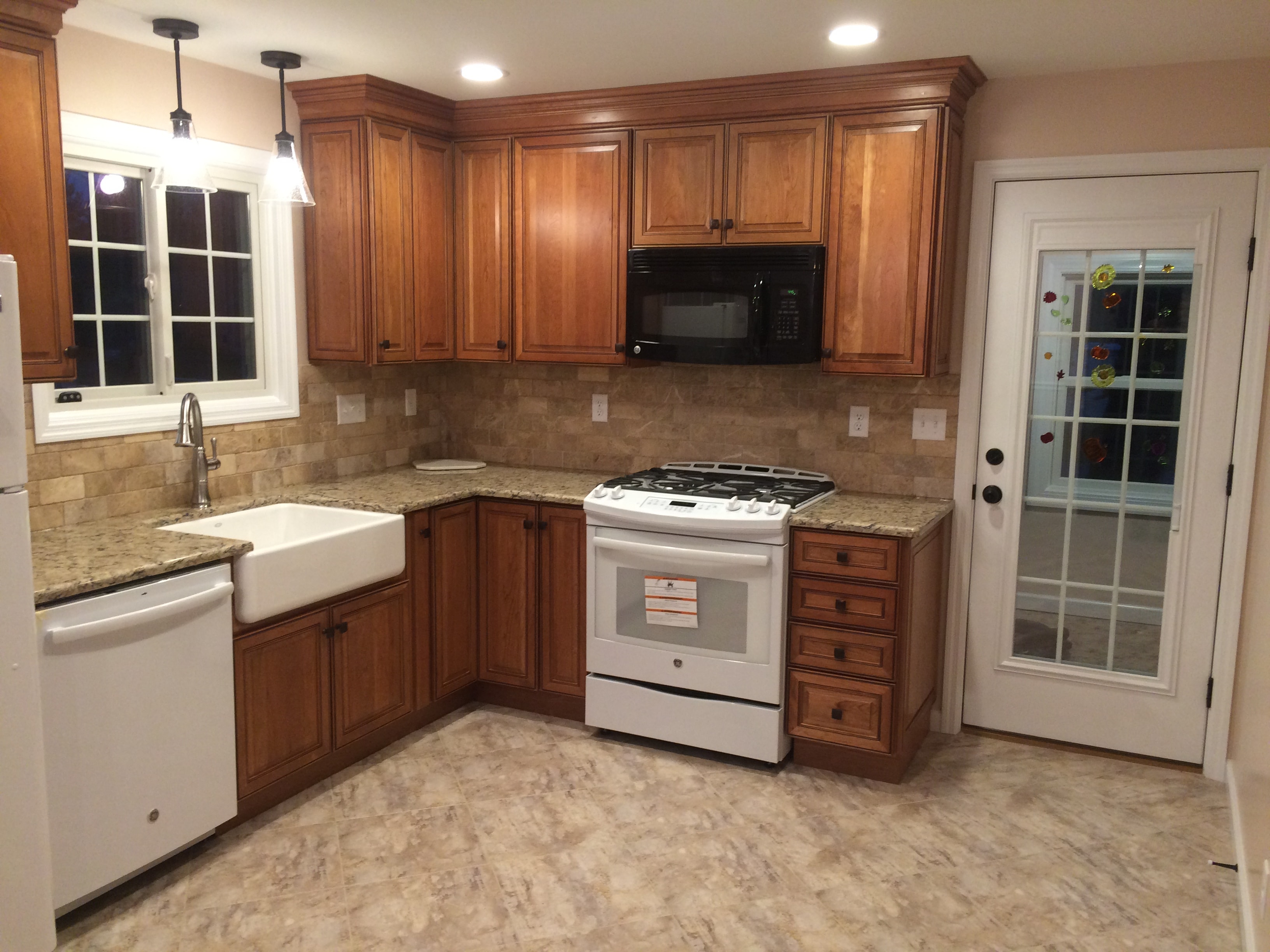 Cherry cabinet kitchen remodel - angled wide shot showing pendant lights, window, and refrigerator