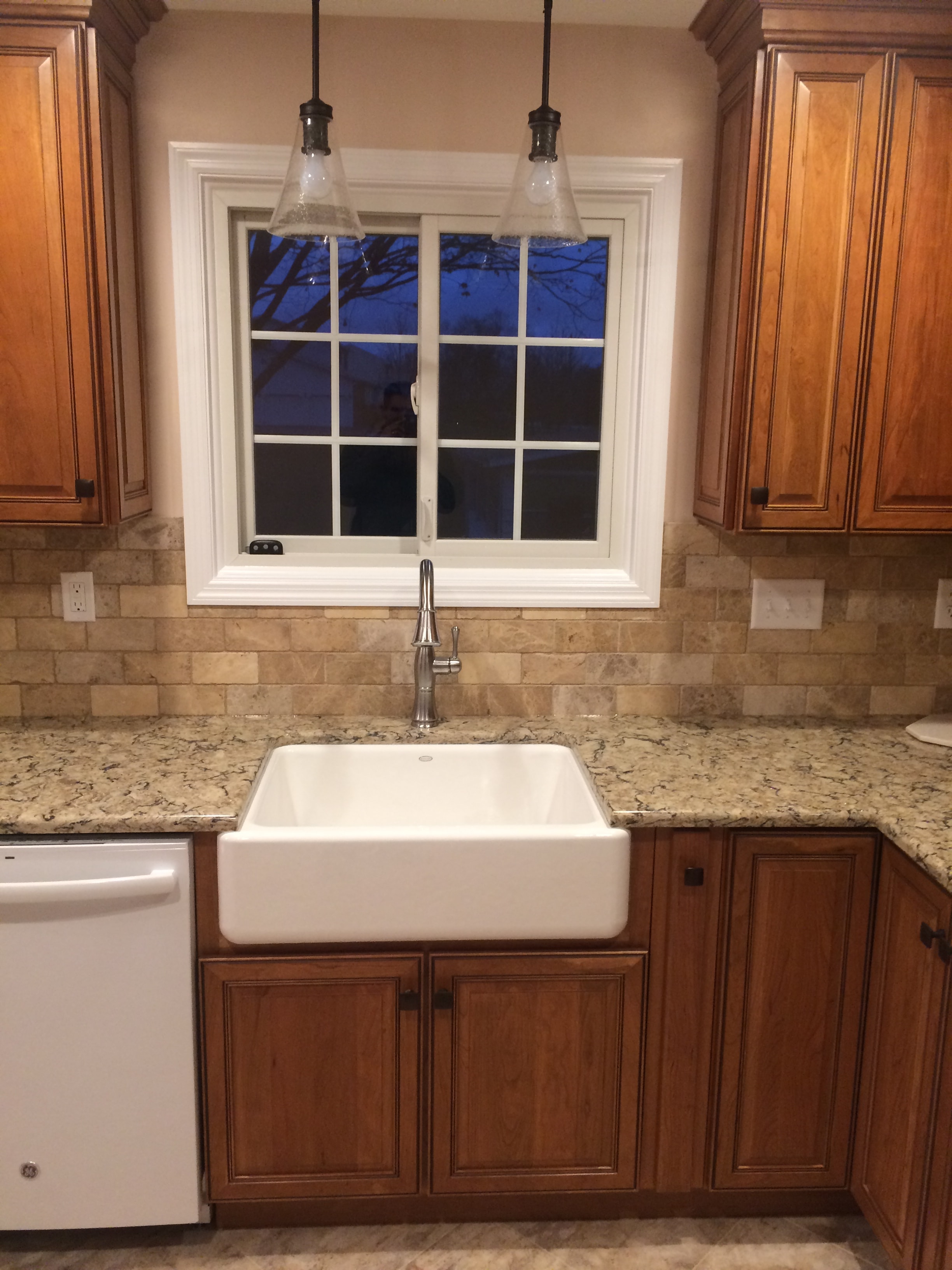Cherry cabinet kitchen remodel - farmhouse sink detail with travertine backsplash and cherry cabinet doors