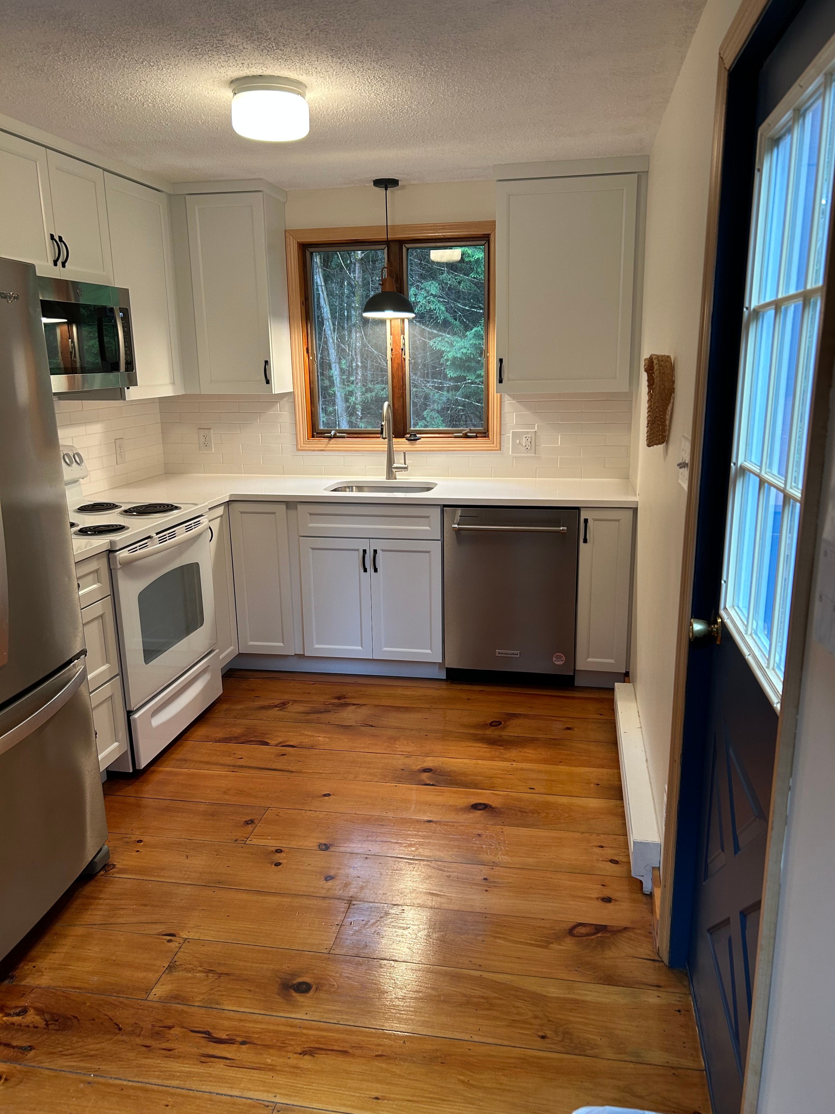 Schroon Lake kitchen remodel - full overview with white shaker cabinetry, subway tile, and blue skylight