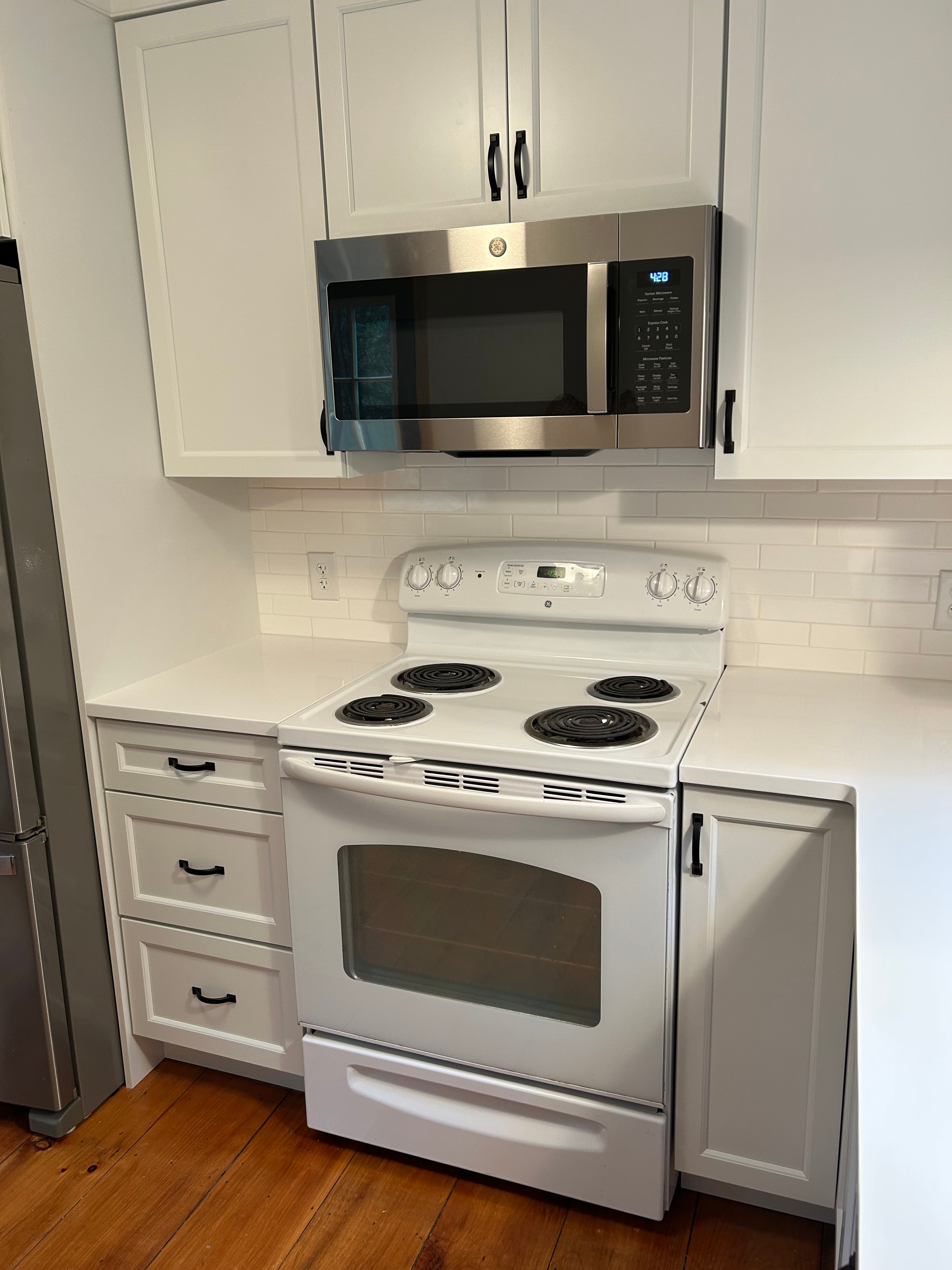Schroon Lake kitchen remodel - appliance wall with built-in microwave, white range, and black hardware