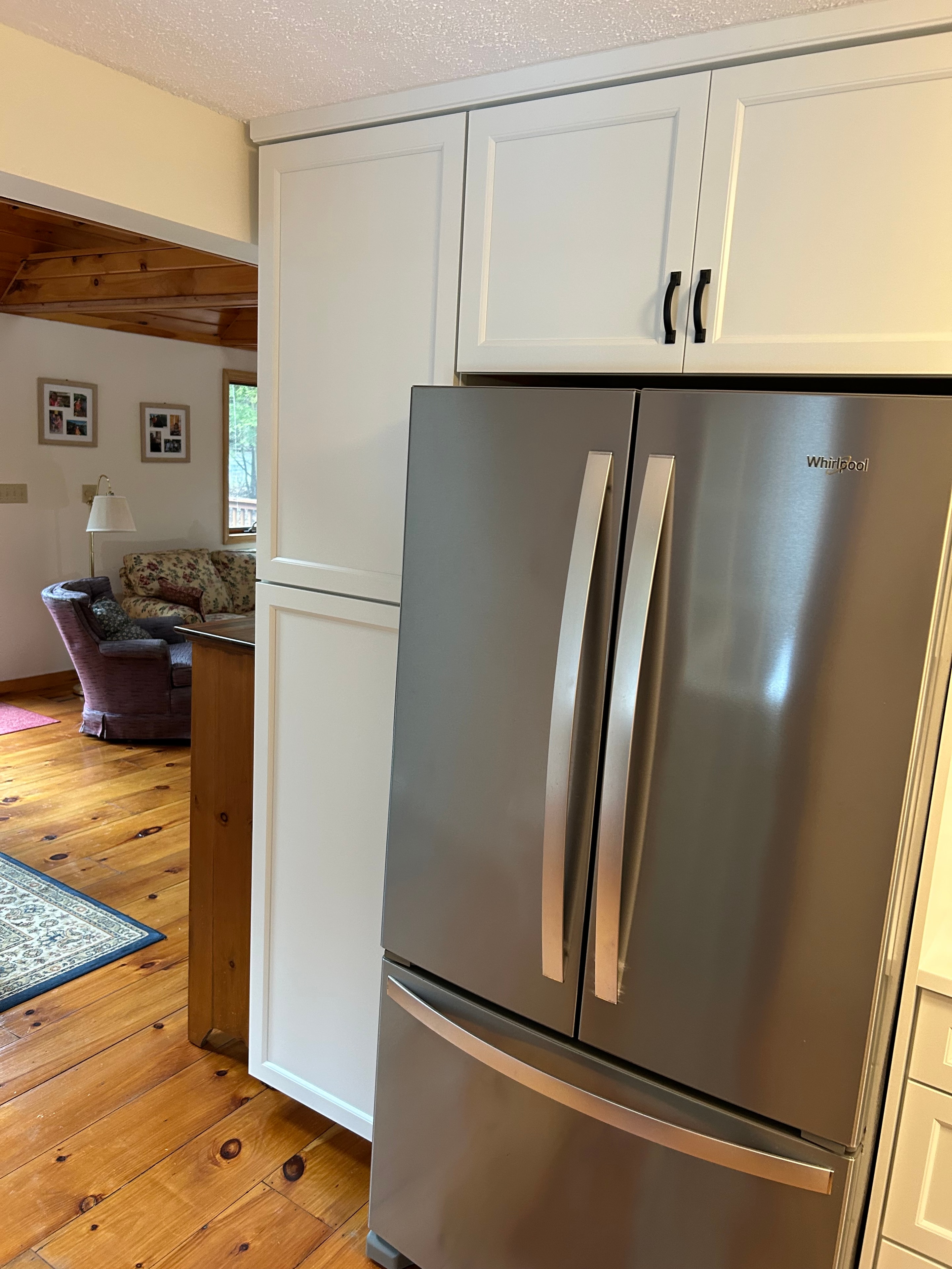 Schroon Lake kitchen remodel - Whirlpool stainless refrigerator flanked by white cabinetry
